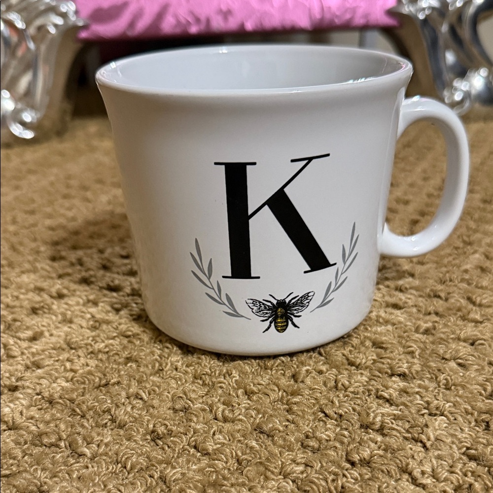 Mug (white) with the letter “K” on it.